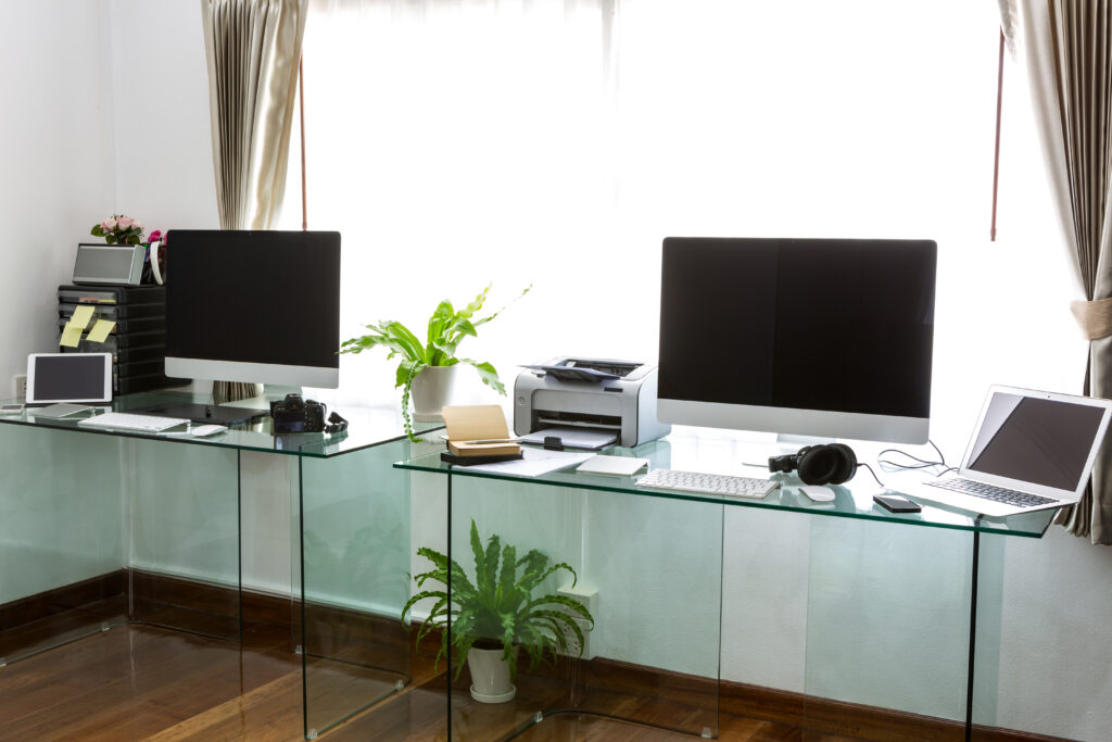 cluttered home office with computers in front of a window